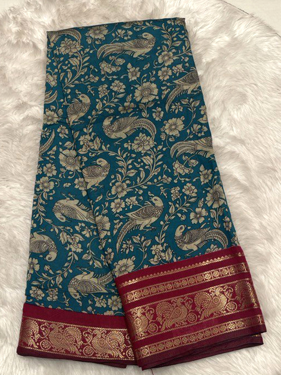 Teal blue Chhagal silk saree with floral Kalamkari prints and a rich maroon contrast gold zari border.
