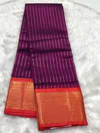 A deep magenta Assam silk saree with vertical gold zari lines and a contrasting red border enriched with dense gold thread work.