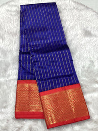 A royal blue Assam pattu saree featuring vertical gold stripes and a traditional heavy red and gold zari border.