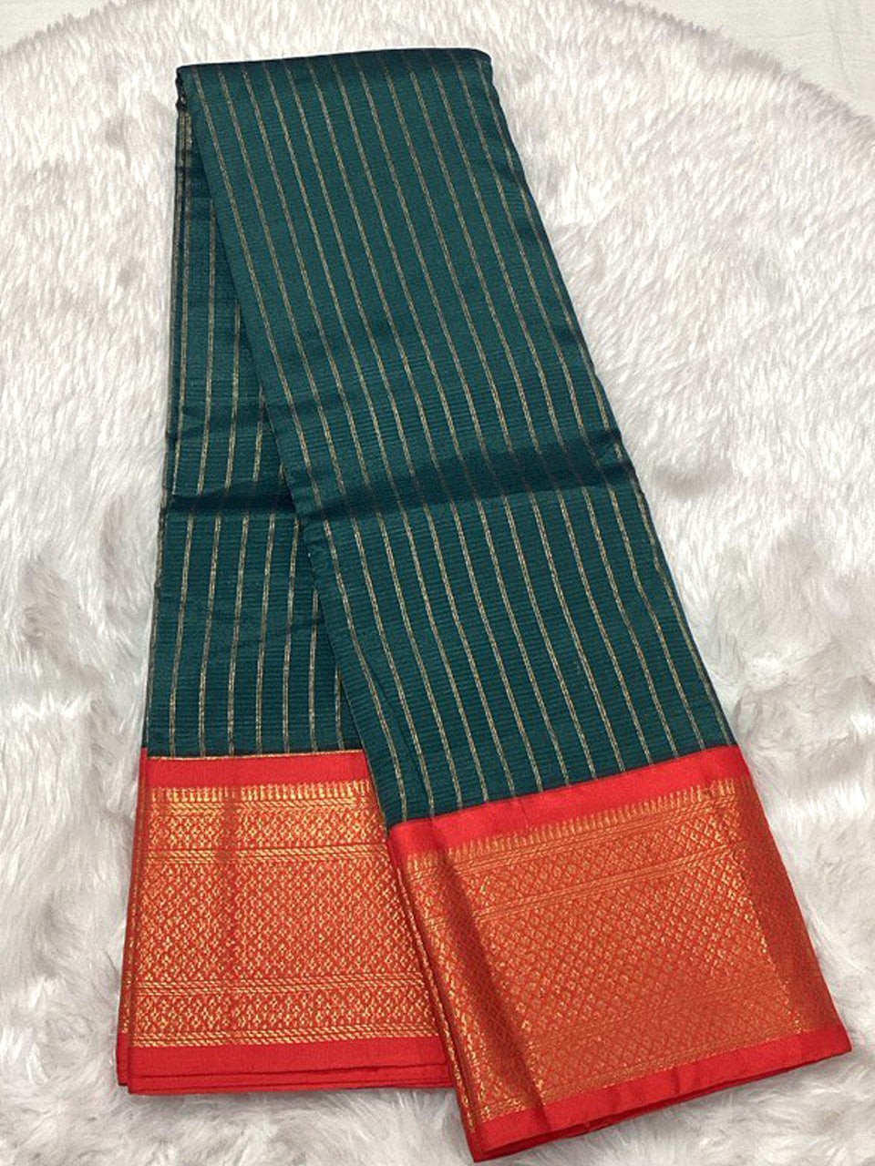 A forest green Assam silk saree with vertical gold zari stripes and a vibrant red border featuring classic golden motifs.