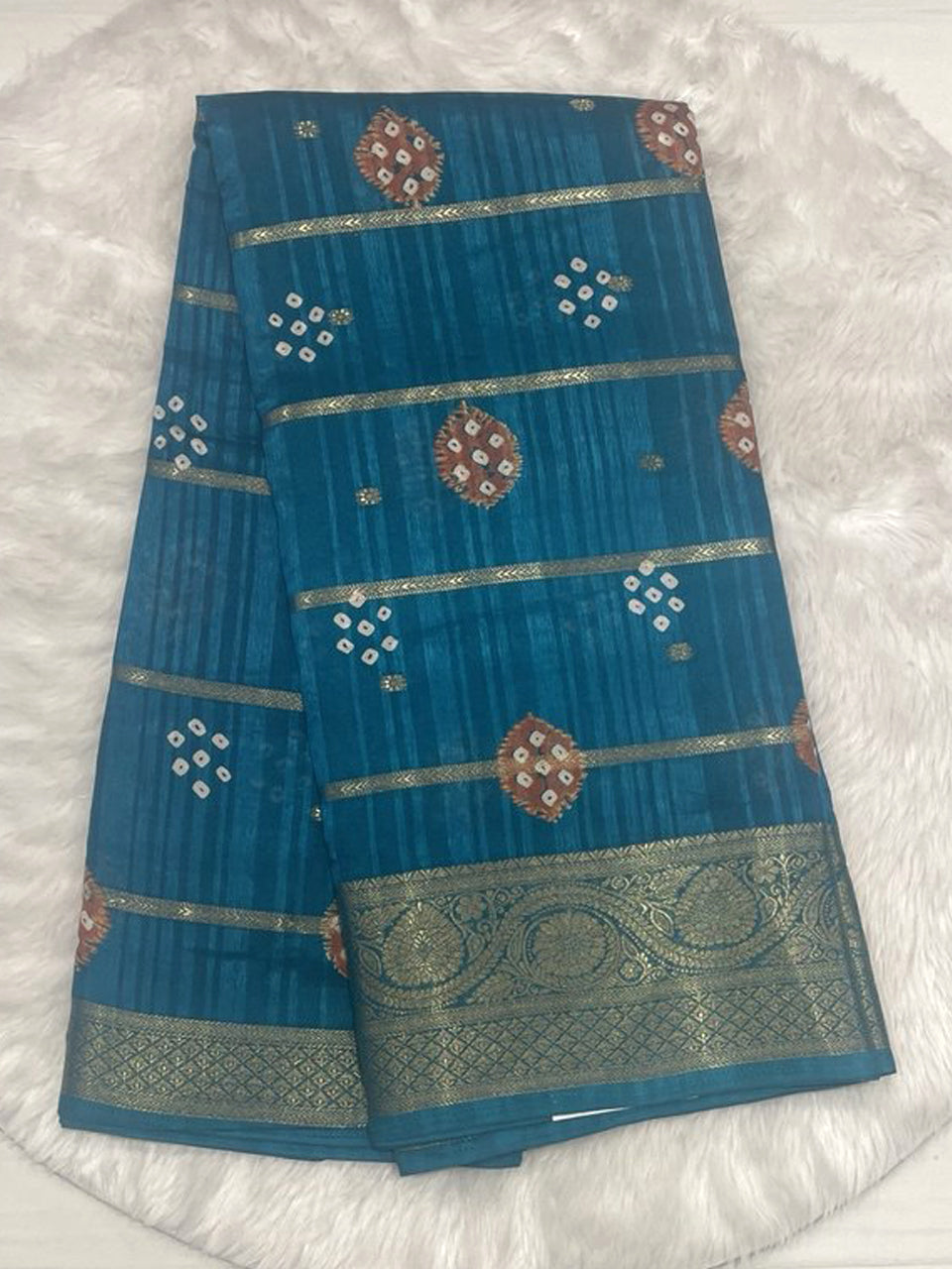 Teal blue Bailu jute saree featuring horizontal zari lines, bandhani motif butas, and a rich traditional gold woven border.