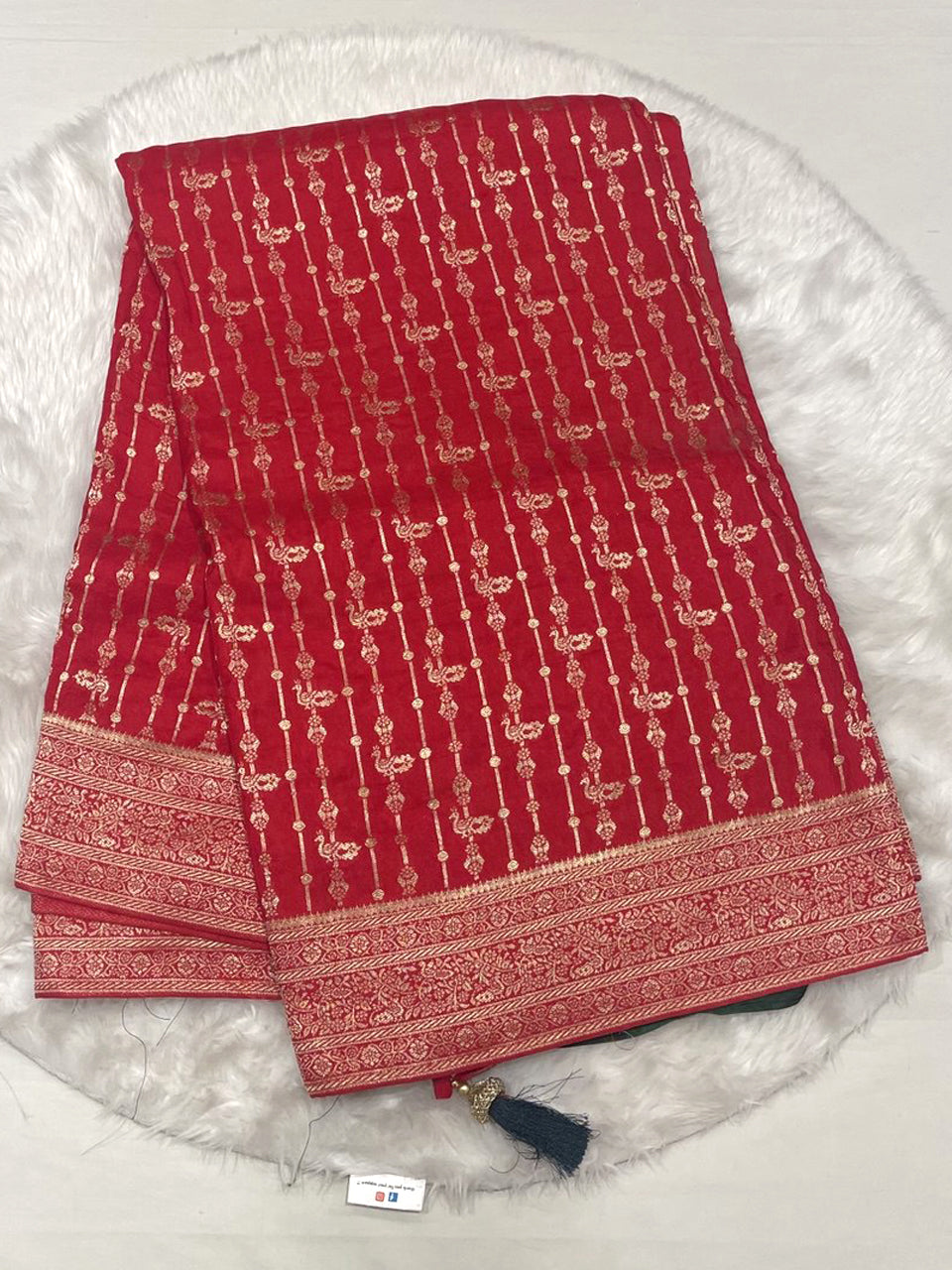 Red Banarasi fancy saree with intricate vertical gold zari weaving and dark green contrast tassels.