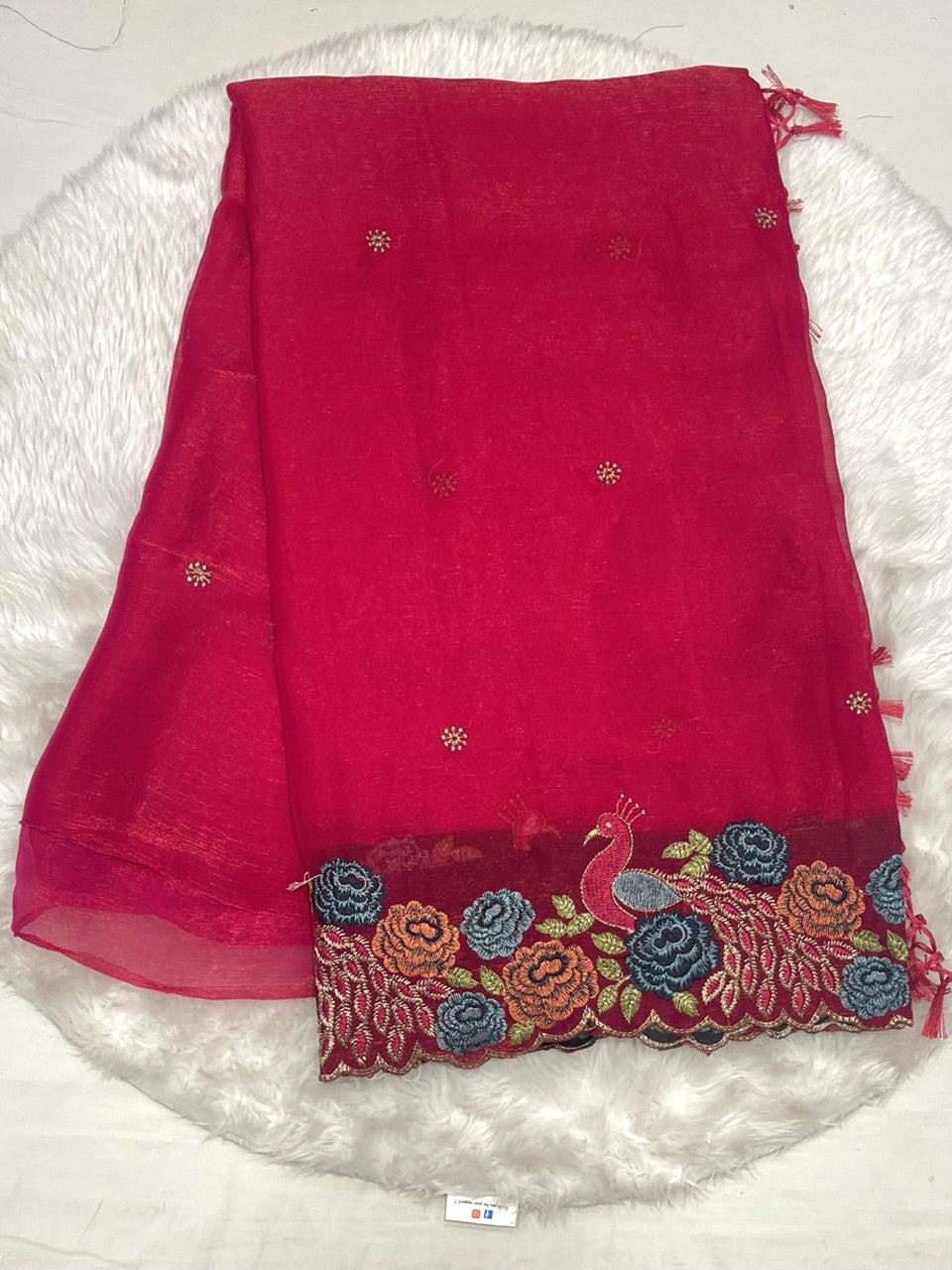 Red chiffon silk saree with small gold buttis and a heavy cutwork embroidery border with peacock motifs.
