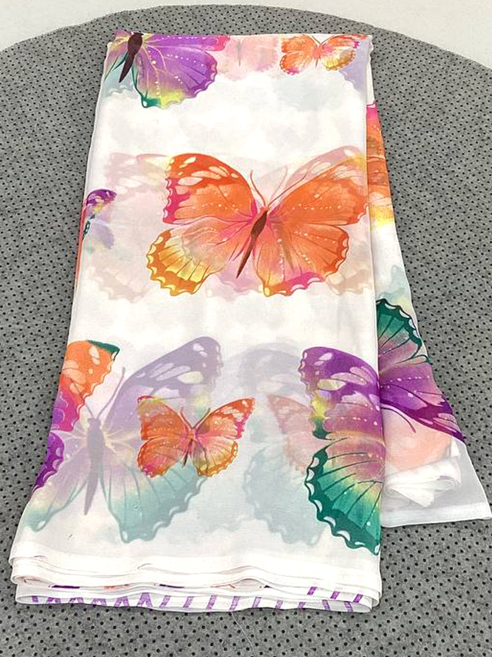 Folded fabric with colorful butterfly design on a gray surface