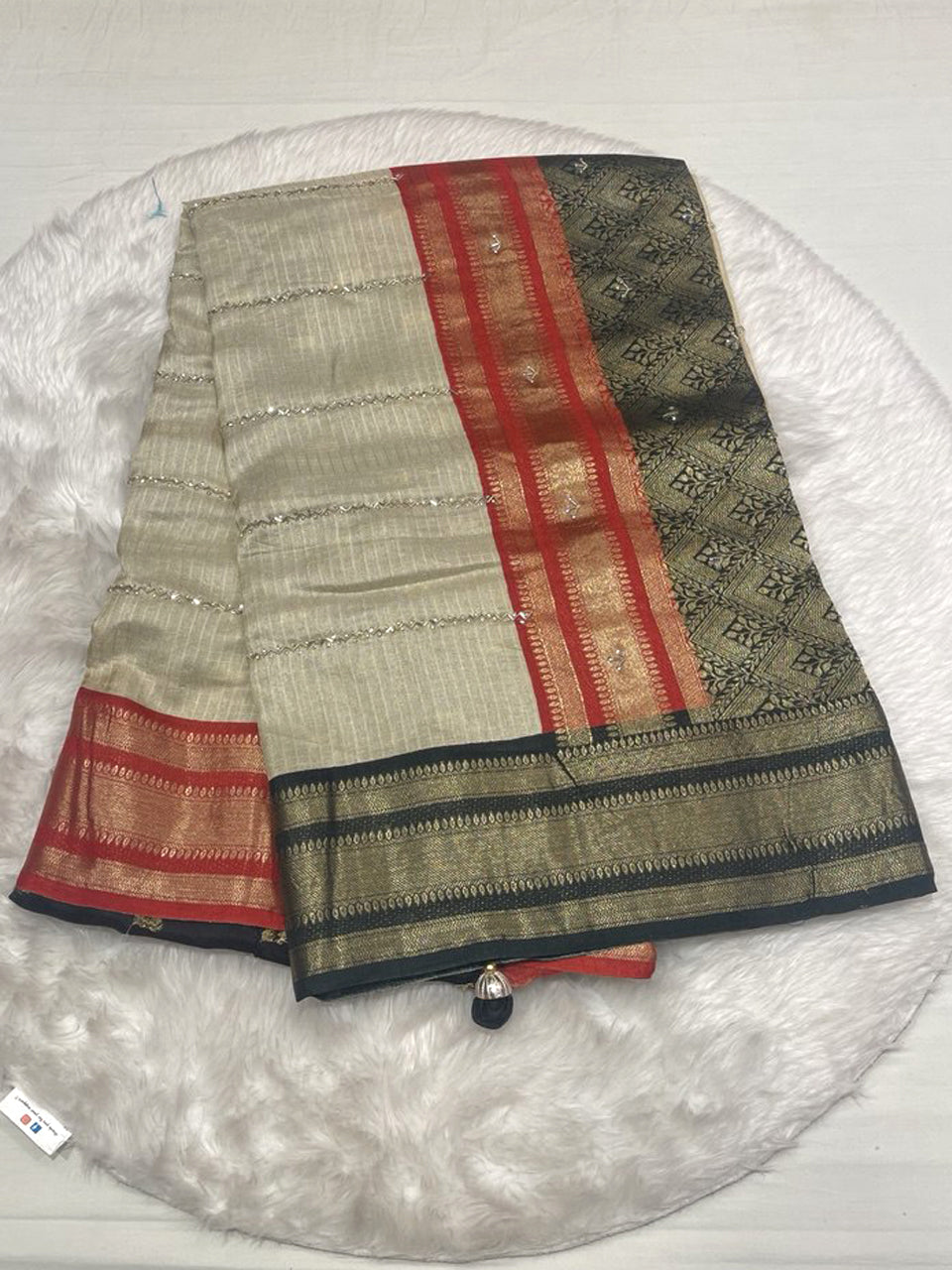 Cream Gadwal silk saree with red and black zari border and horizontal sequence stripes.