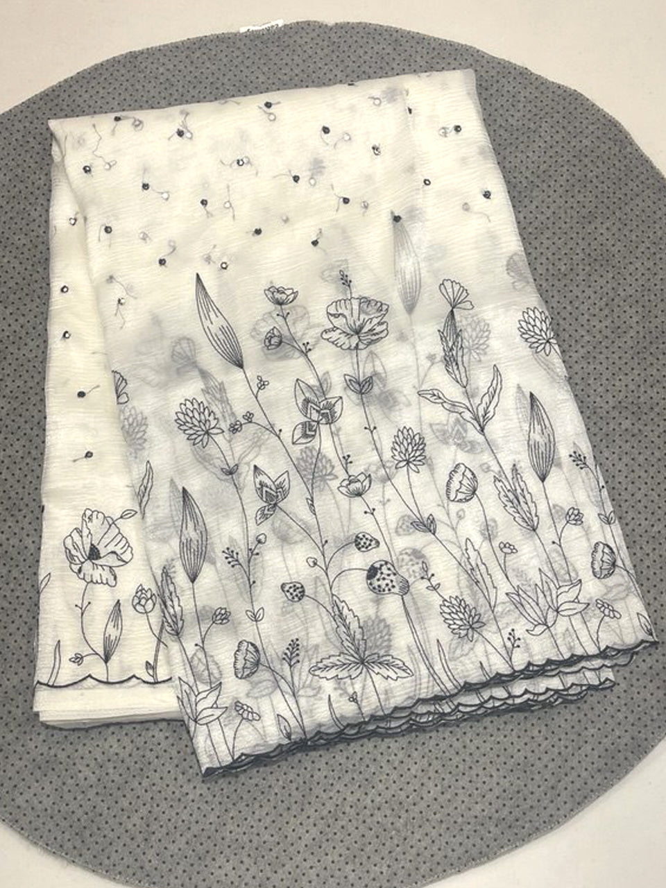 Off-white Jimmy Choo saree featuring contrast black floral embroidery and a scalloped cutwork border.