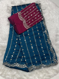 Peacock blue jute silk saree with silver/gold zari lines and magenta designer blouse with cutwork details.