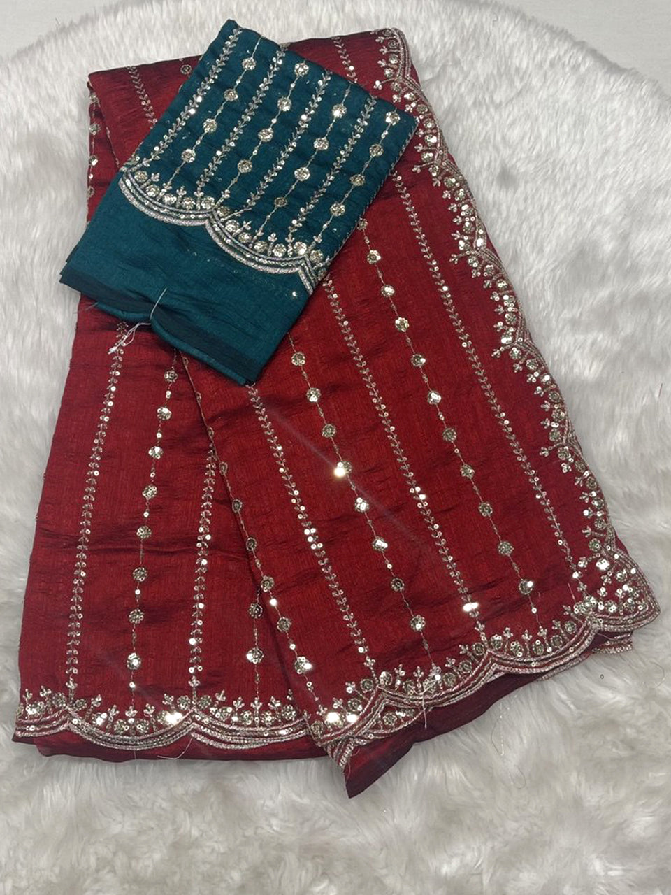 Maroon red jute silk saree with vertical sequin work and cutwork border, paired with a teal green designer blouse.
