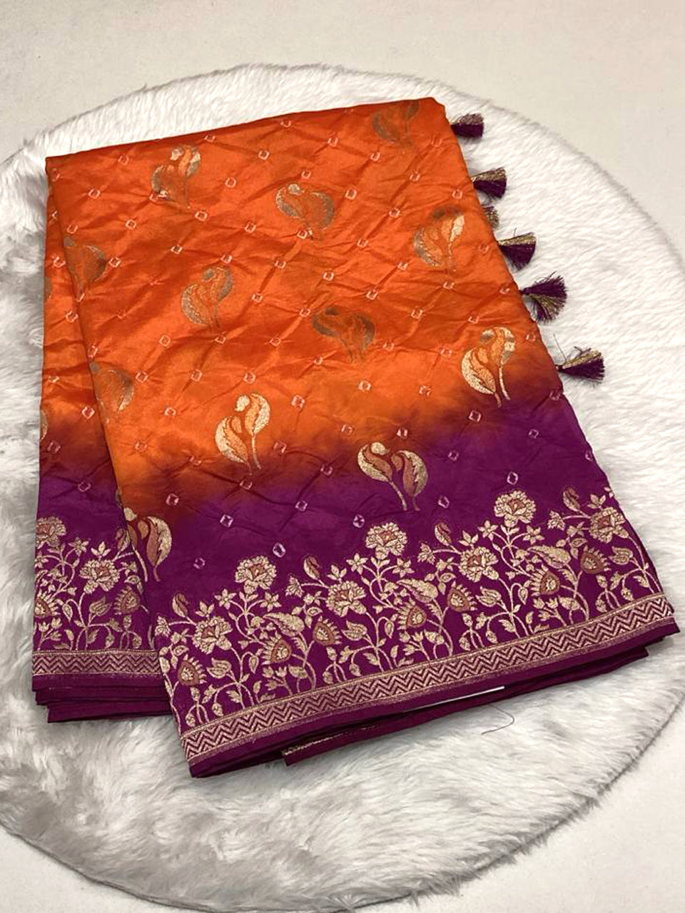 Orange and purple dual-tone Bandhani silk saree with gold zari floral border and tassels.
