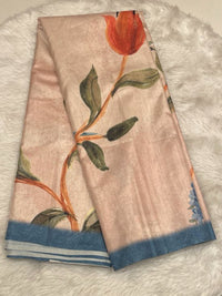 A champagne-beige raw silk saree featuring a large-scale hand-painted style floral print with a vibrant orange tulip and green leaves, finished with a contrasting slate blue border and silver zari stripes.