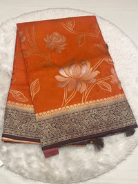 Vibrant orange Russian viscose saree with dark brown designer border and silver floral weave.