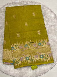 Elegant olive green Samurai Satin saree showcasing traditional gold butti patterns and a vibrant woven flower border.