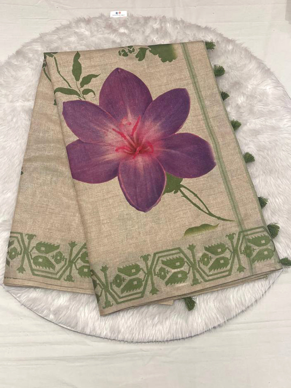 Beige semi Tussar saree featuring a bold purple flower print and a contrasting leaf green woven border.