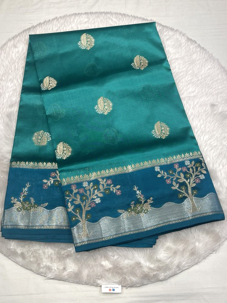 Teal green Mango silk saree with gold buttas and blue tree motif border.